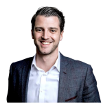 Custom WordPress Web Design USA – Secure & SEO-Ready 9 Headshot of a smiling man with dark hair wearing a suit jacket and white shirt against a black background.